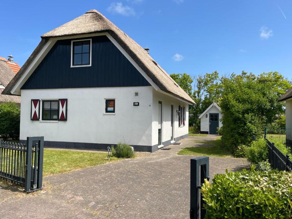 a white and black house with a thatched roof at Buitenplaats 108 in Callantsoog