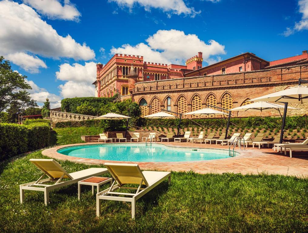 a swimming pool with chairs and a large building at Il Castello di San Ruffino in Lari