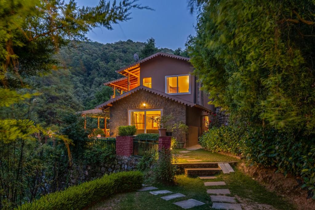 a house in the woods at night at SaffronStays Plaksha - 2BR pet-friendly homestay with Himalayan views, verandah dining & bonfire near Chauli ki Jali in Mukteshwar