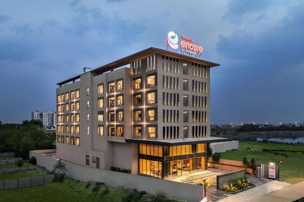 a hotel building with a sign on top of it at Ramada Encore by Wyndham Indore Nipania in Indore