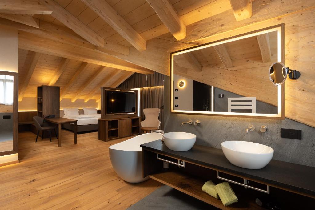 uma casa de banho com 2 lavatórios e um espelho grande em Camino Rustic Chic Hotel em Livigno