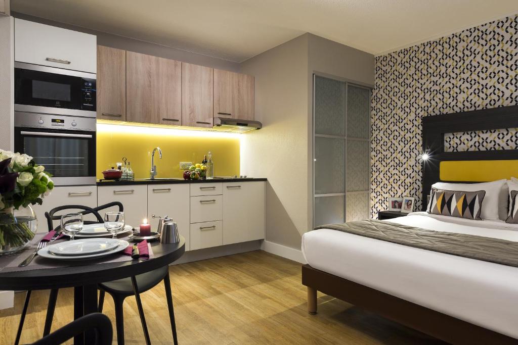 um quarto com uma cama, uma mesa e uma cozinha em Citadines Tour Eiffel Paris em Paris
