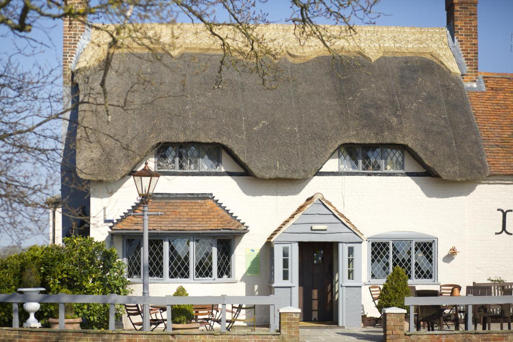 uma casa com telhado de palha e uma mesa em frente em Crab & Boar em Newbury