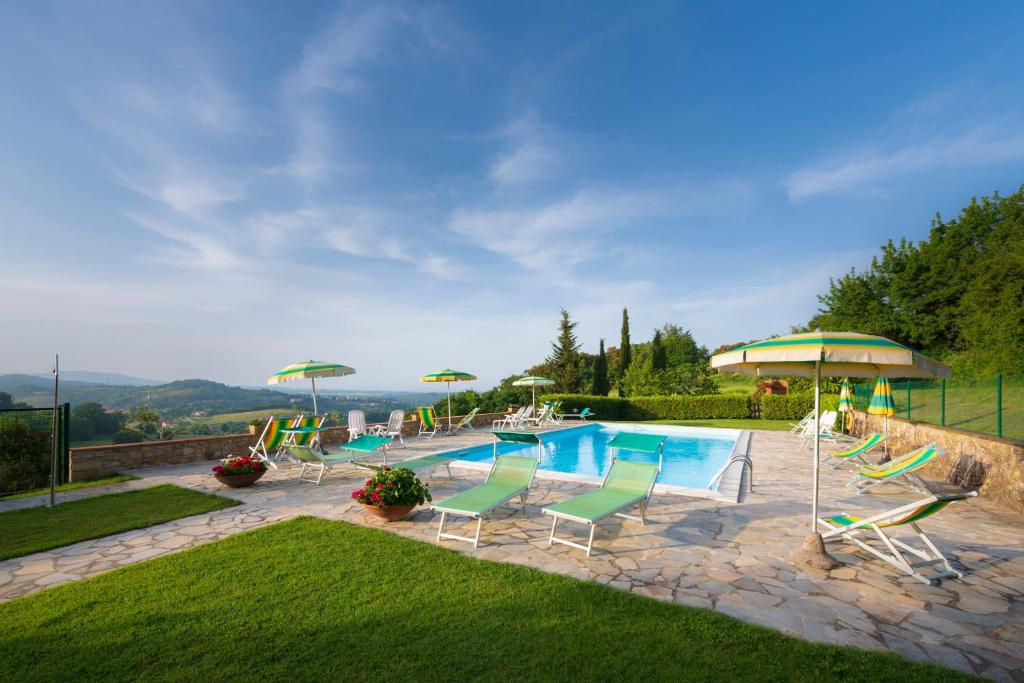 a swimming pool with lawn chairs and umbrellas at Monti 1824 - Apartments & Cottages in Casole dʼElsa