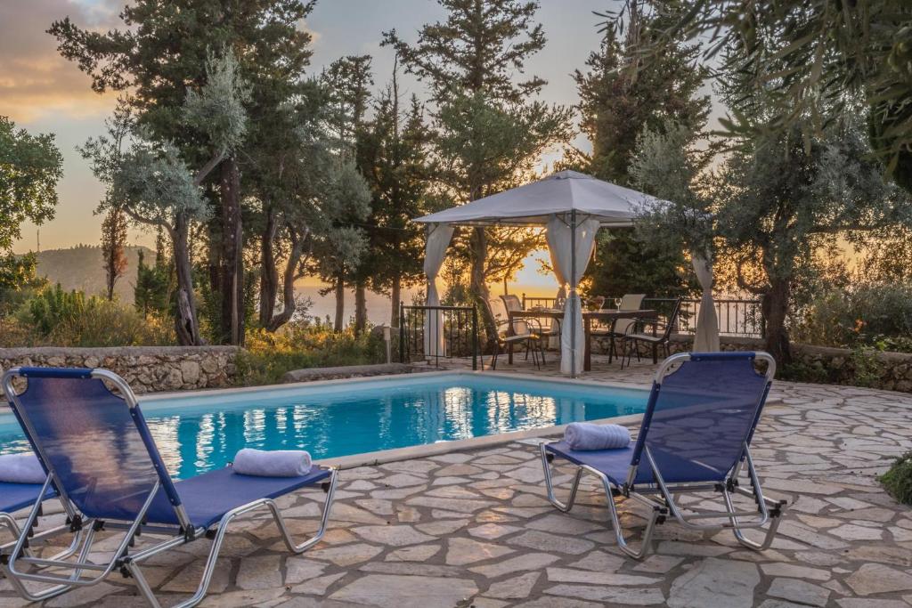 two chairs and an umbrella next to a swimming pool at Agios Nikitas Nature Villas in Komílion