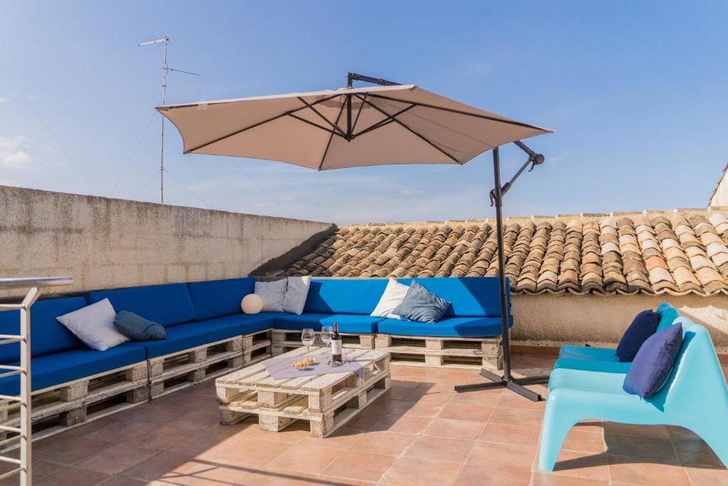 un divano blu e un ombrellone su un patio di Casa Lina con terrazza a Canicattini Bagni