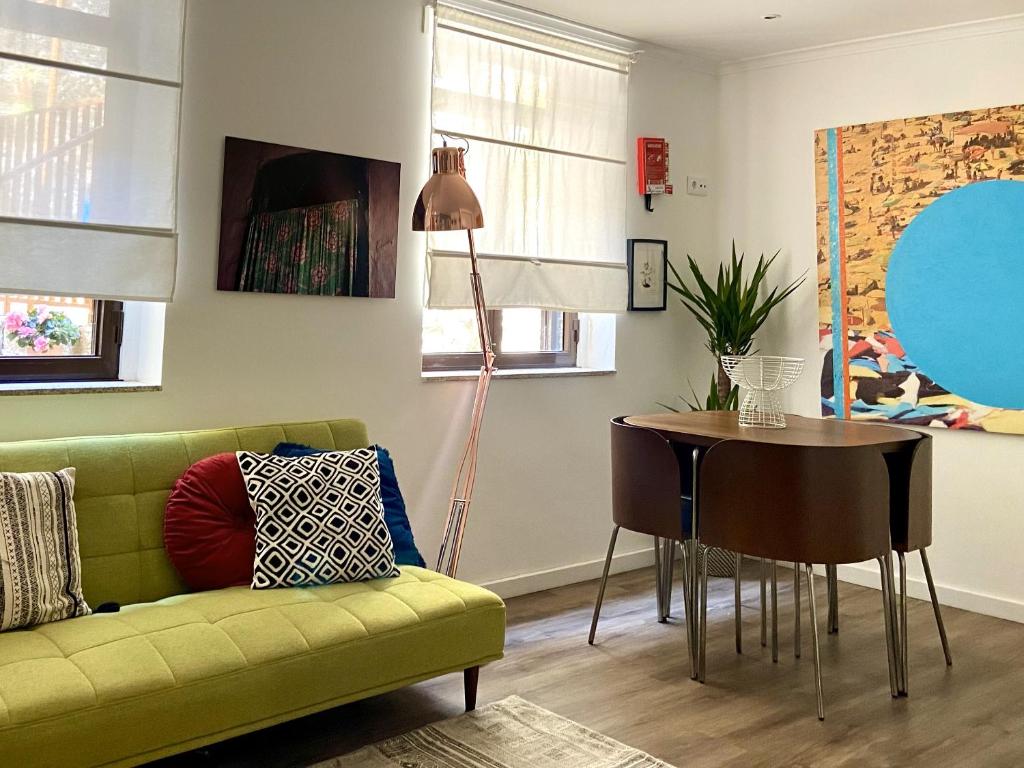 uma sala de estar com um sofá verde e uma mesa em Ribeira Art Terrace no Porto
