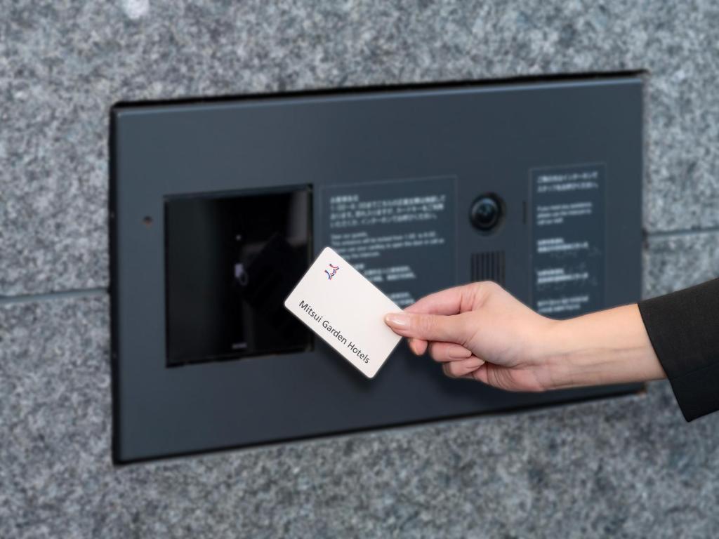 a person holding a piece of paper in a microwave at Mitsui Garden Hotel Kumamoto in Kumamoto