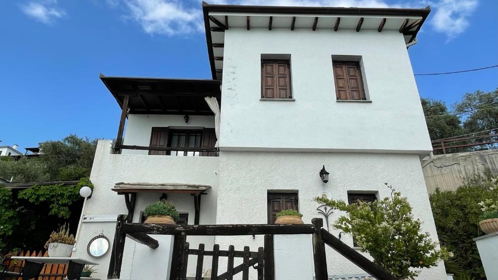 a white house with brown windows and a fence at Iris Sea View Villa in Afissos