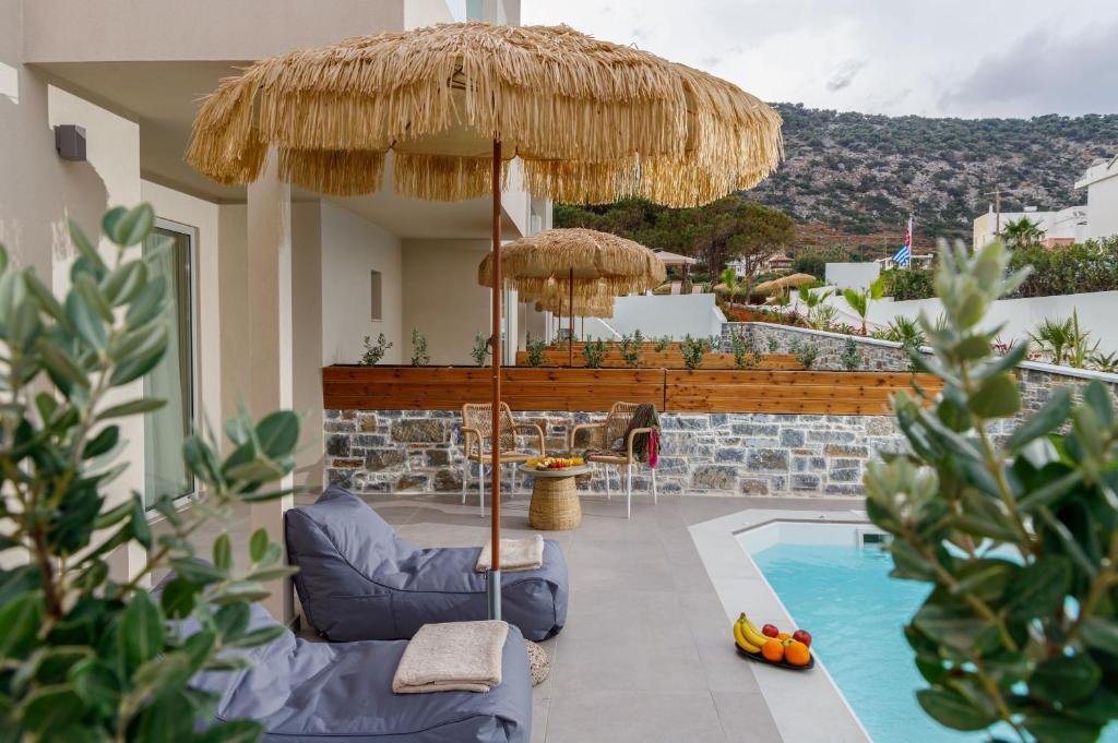 a patio with a chair and an umbrella and a pool at Anassa Suites Stalis by Estia "Adults Only" in Stalida