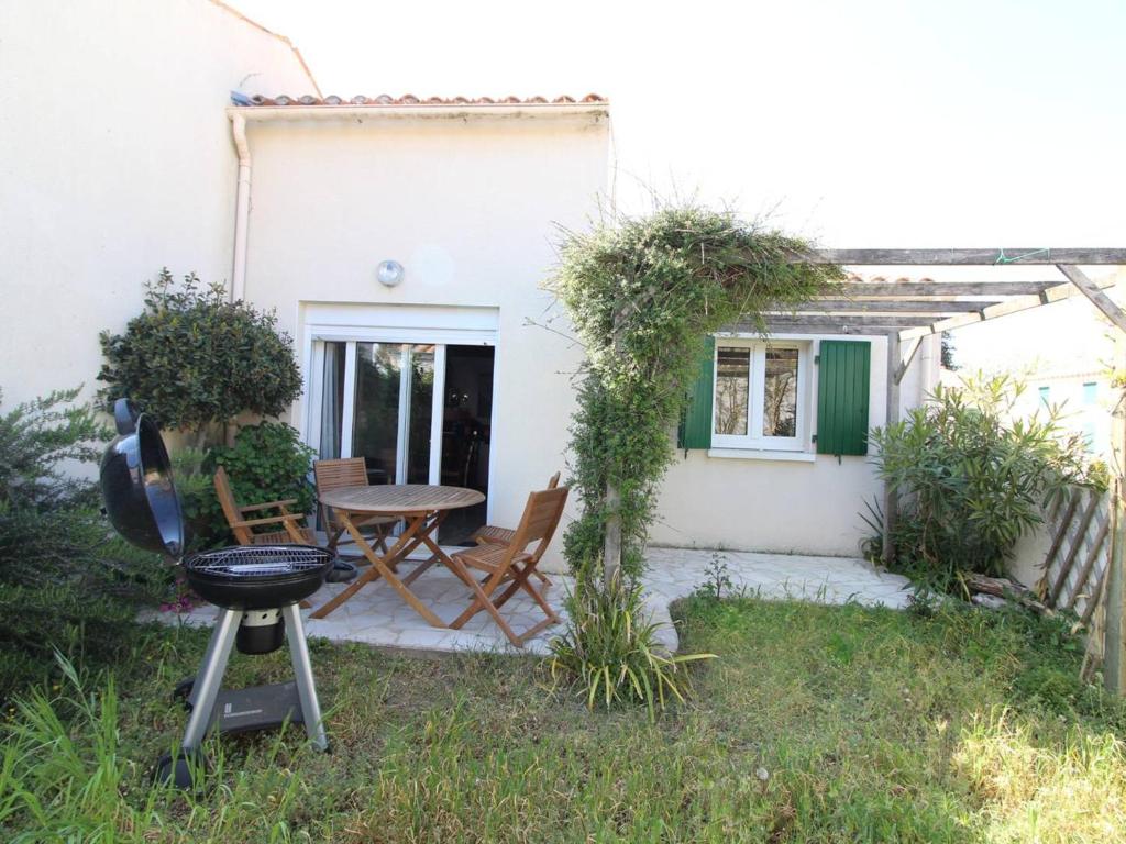 un patio avec une table et des chaises devant une maison dans l'établissement Maison de vacances 3 pièces à Saint-Pierre-d'Oléron, 4 couchages, terrasse, animaux acceptés - FR-1-246A-110, à Saint-Pierre-dʼOléron