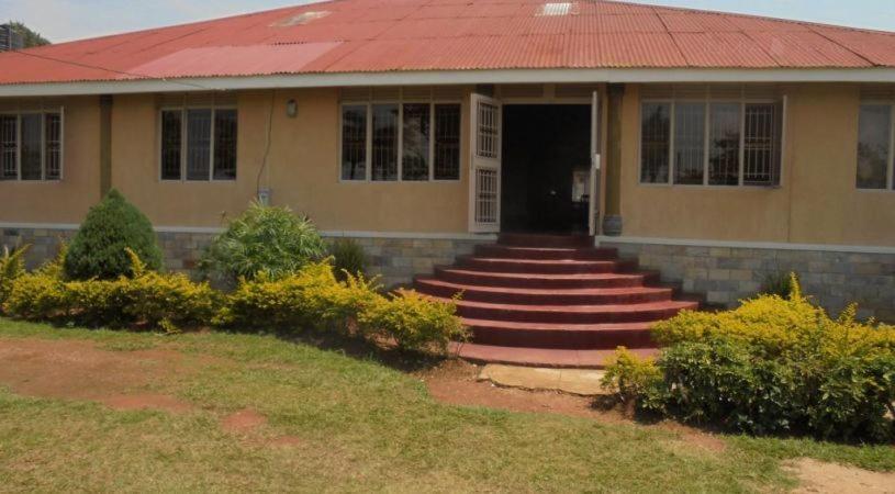 una casa con tetto rosso e scale per una porta di Botanical Skyway Inn Entebbe a Entebbe