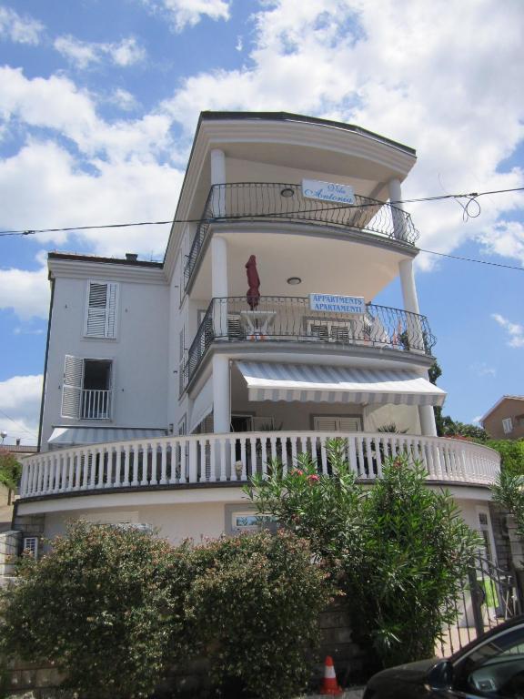 a tall white building with a balcony on it at Apartments Antonia in Malinska