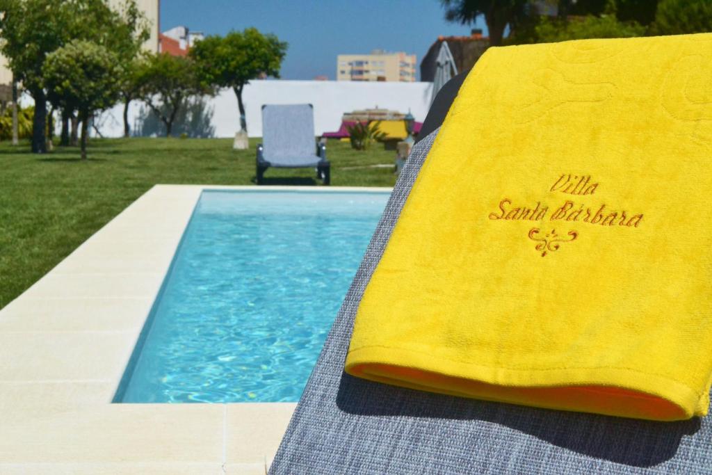 une serviette jaune posée à côté d'une piscine dans l'établissement Villa Santa Bárbara, à Vila Nova de Gaia