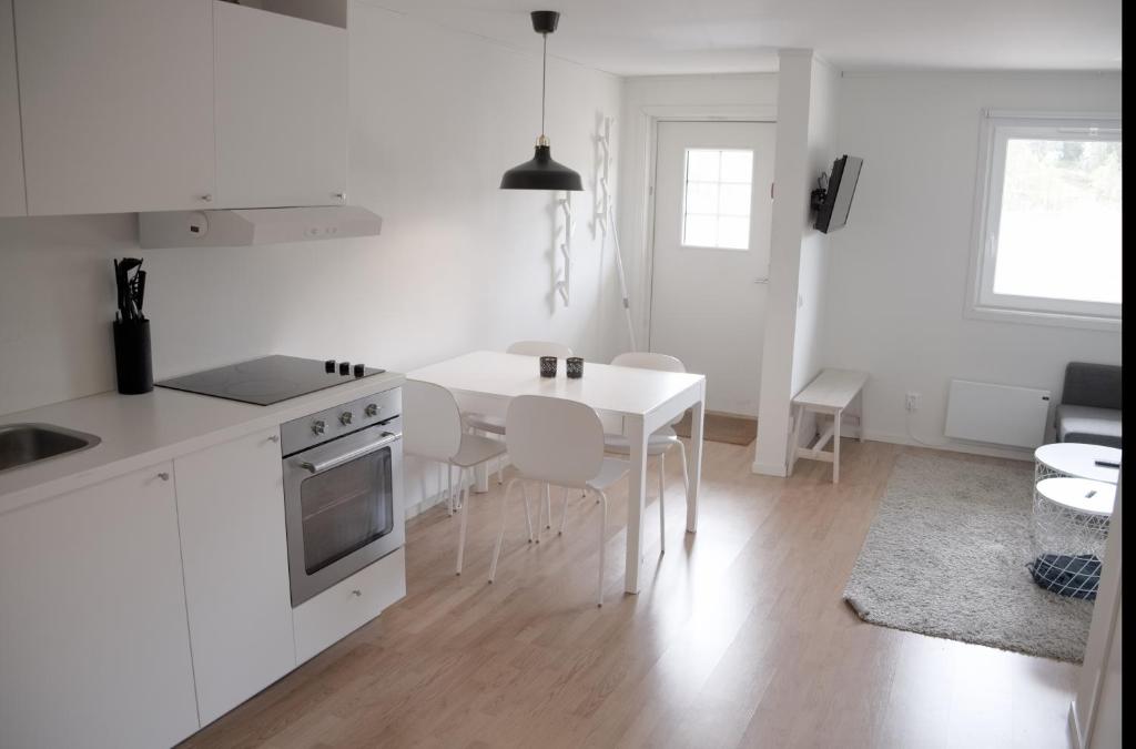 uma cozinha branca com uma mesa e cadeiras brancas em Storklinta Skidcenter - Lägenhet em Jörn