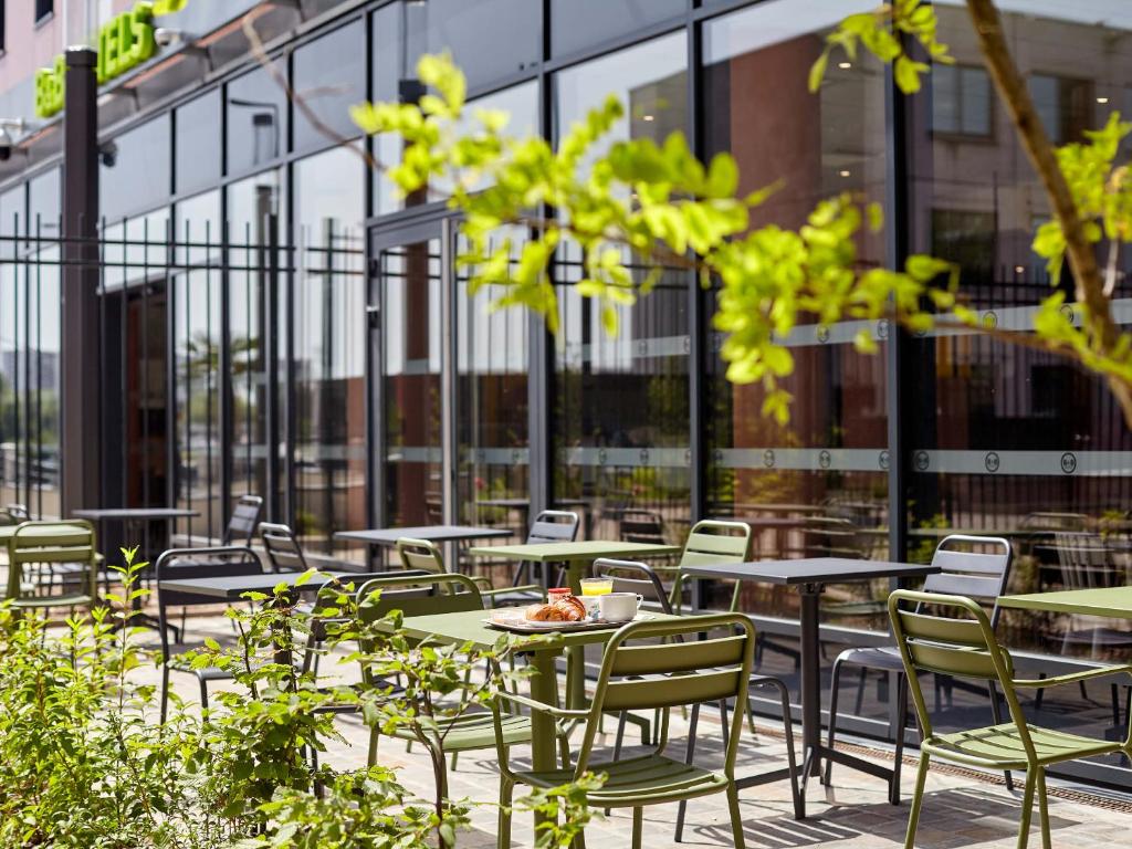 a row of tables and chairs on a patio at B&B HOTEL Argenteuil in Argenteuil