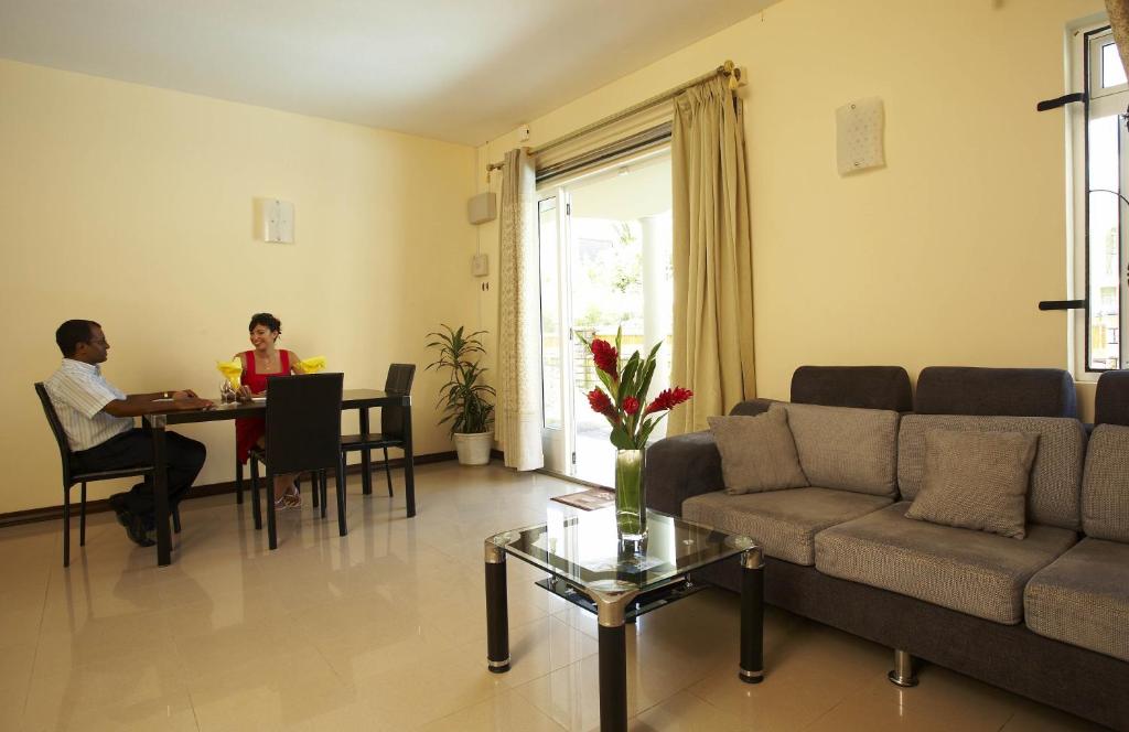 Ein Mann und eine Frau sitzen an einem Tisch im Wohnzimmer in der Unterkunft Jet Villa in Flic-en-Flac