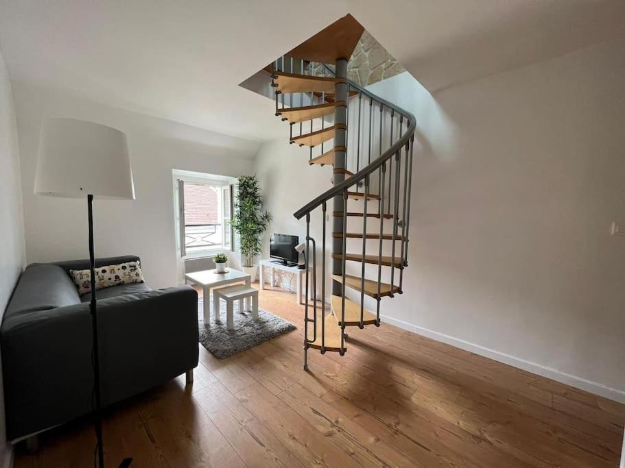 - un escalier en colimaçon dans le salon doté d'un canapé dans l'établissement Au cœur du Bourg - La Celle St Cloud., à La Celle-Saint-Cloud