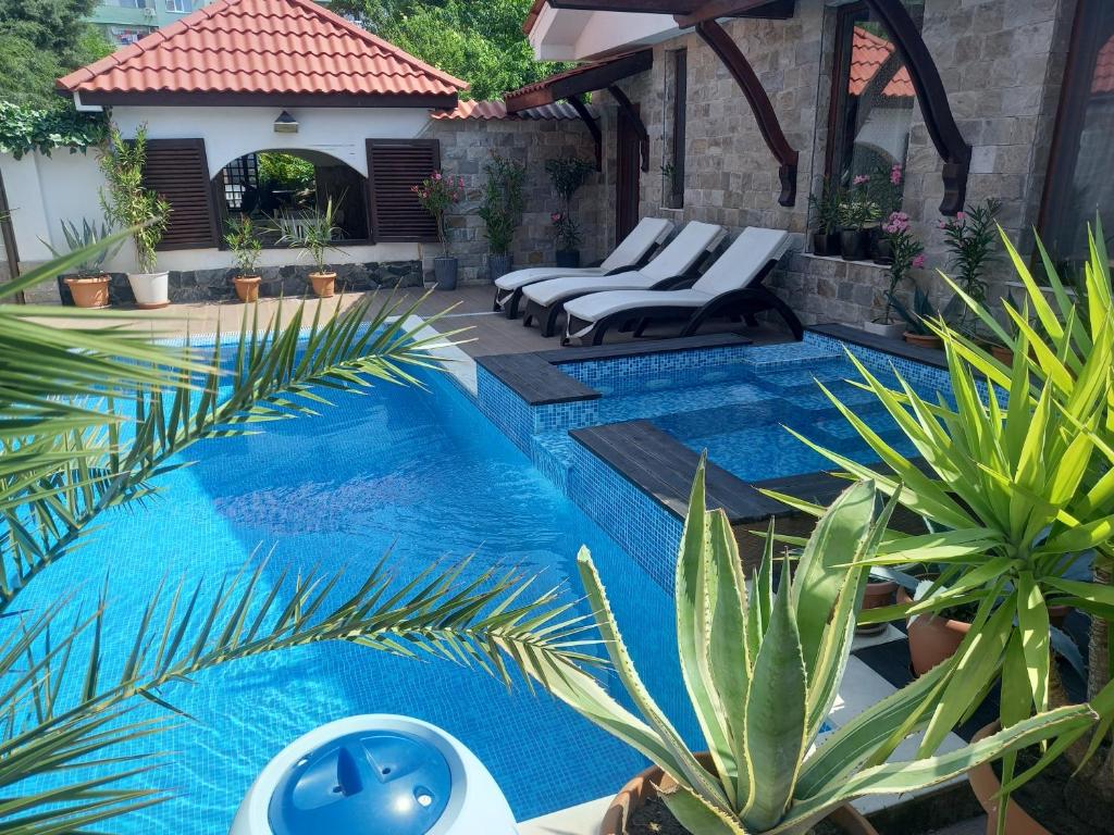 uma piscina com espreguiçadeiras e plantas num quintal em Stariya oreh pool & garden em Vidin
