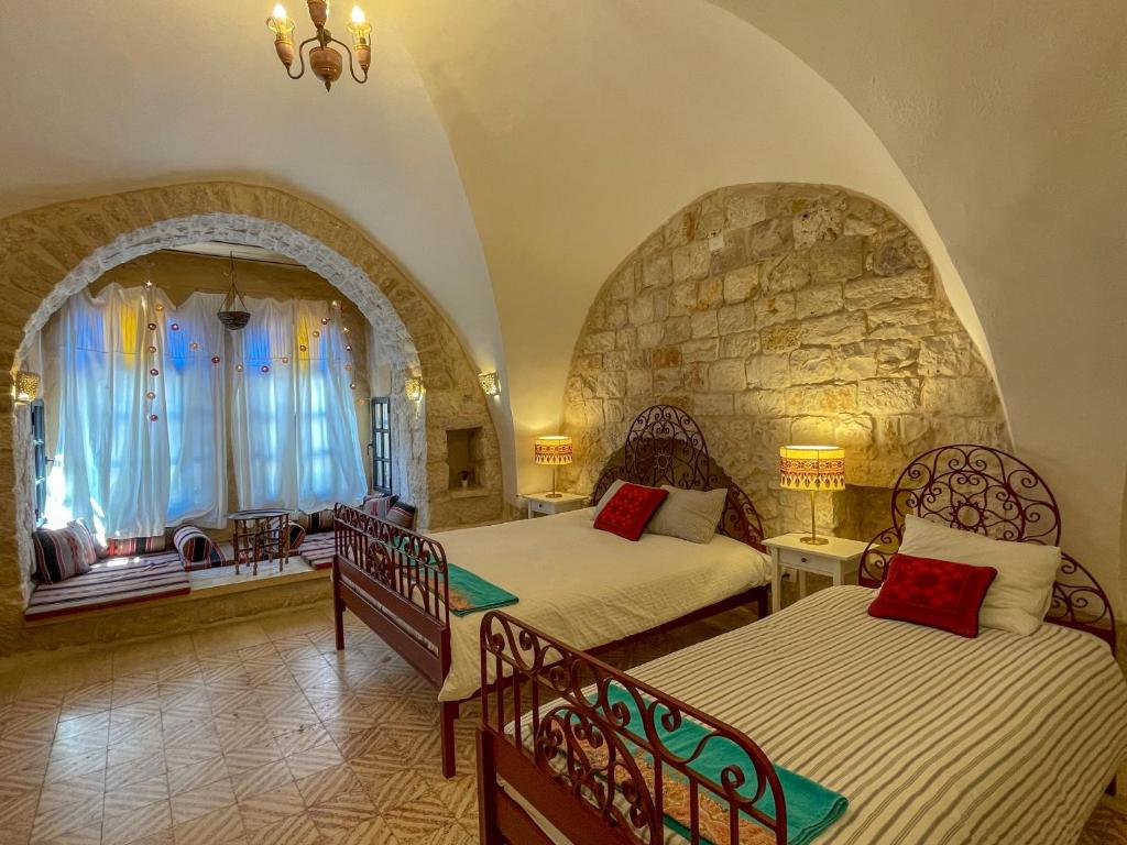 1 dormitorio con 2 camas y pared de piedra en Dar al Majus en Bethlehem