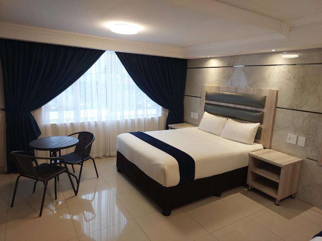 謝普斯敦港的住宿－Bayside Taj Hotel，酒店客房带一张床、一张桌子和椅子