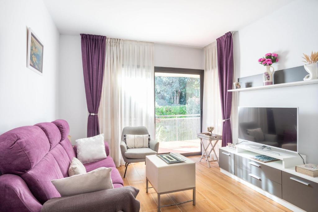 Una sala de estar con un sofá morado y un televisor. en Apartment Sa Boadella beach, Lloret de Mar - Costa Brava, en Lloret de Mar