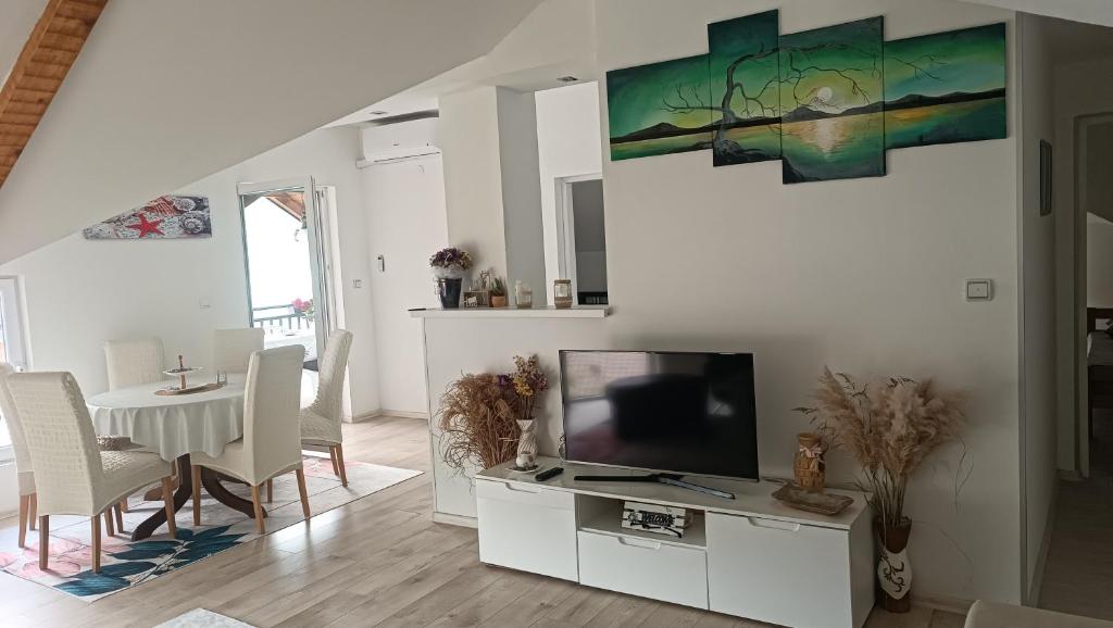 a living room with a tv and a table with chairs at Lejla apartmani - Jablaničko jezero in Konjic