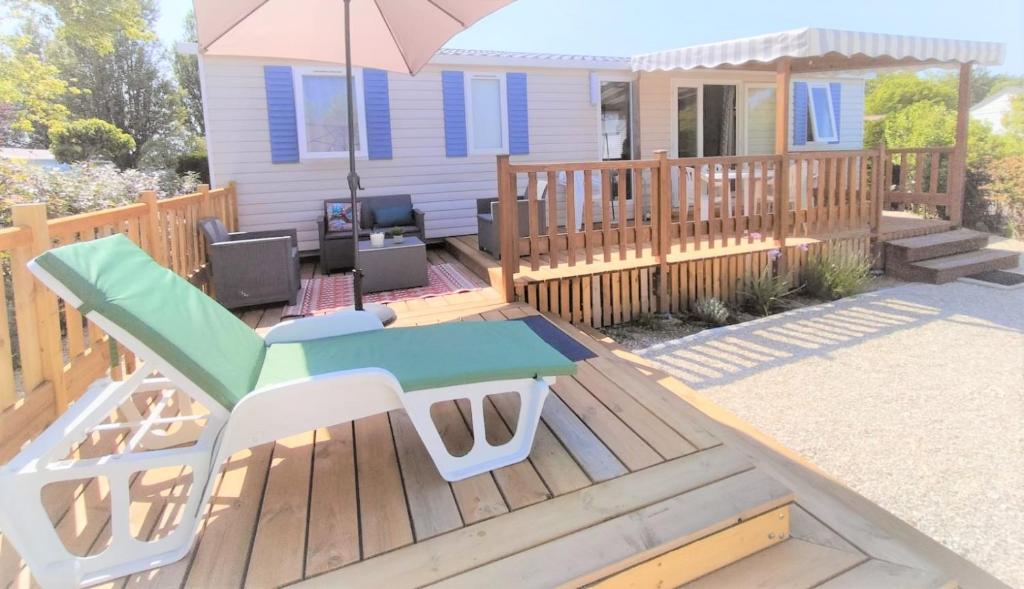 a wooden deck with a table and an umbrella at Coquillages & Crustacés avec Piscine Chauffée & Plage in Marennes