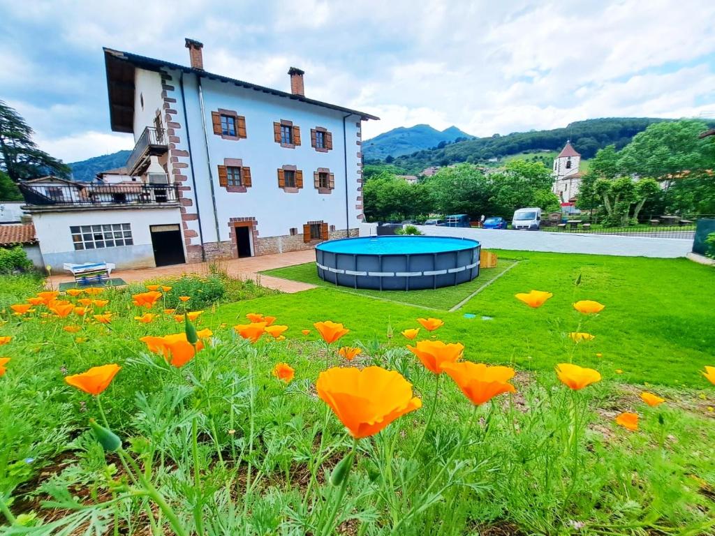 um campo de flores de laranja em frente a um edifício em Casa Rural Betraunea em Sumbilla