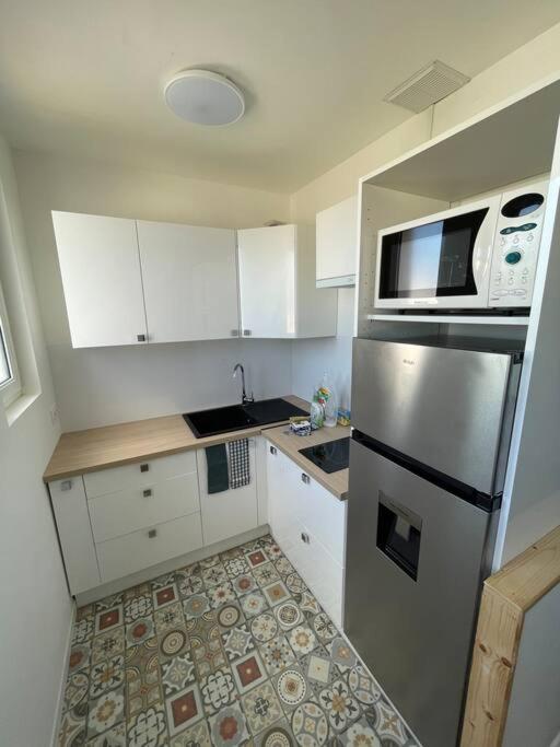 a kitchen with white cabinets and a stainless steel refrigerator at MILO - Appartement T2 Lanester in Lanester