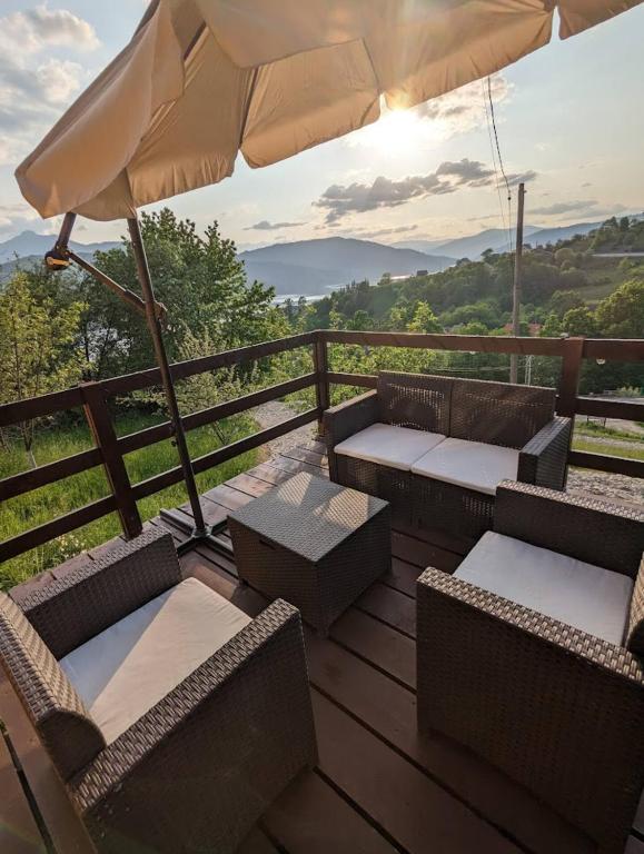 a wooden deck with chairs and an umbrella at Lake House Anemona in Buhalniţa