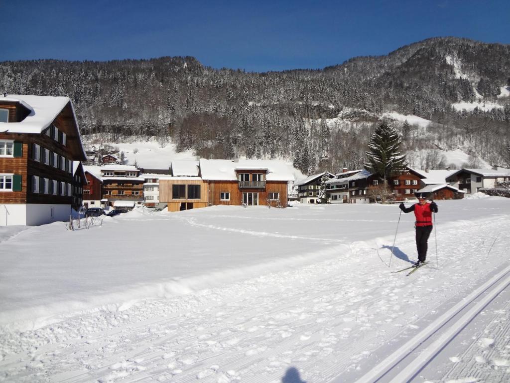 eine Person auf Skiern im Schnee in der Nähe einer Lodge in der Unterkunft Apartment Magdalena in Bezau