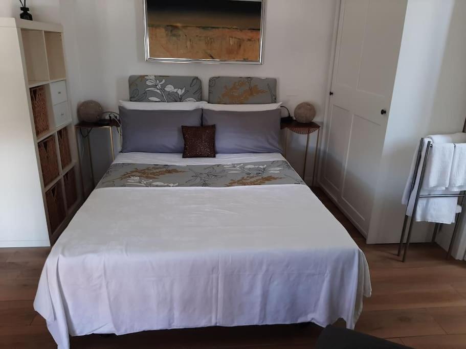 1 dormitorio con 1 cama grande con colcha blanca en Brasil mini casa ,bagno e angolo cottura., en Ladispoli
