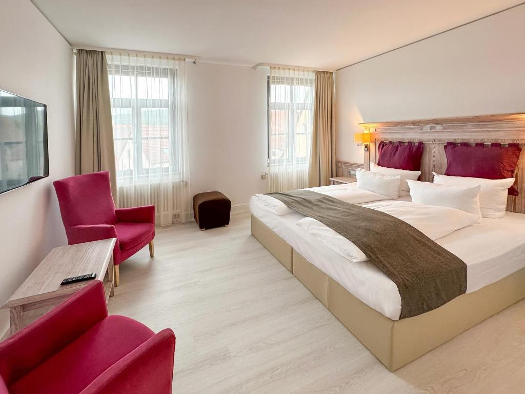 Cette chambre d'hôtel comprend un grand lit et des chaises violettes. dans l'établissement DORMERO Schlosshotel Reichenschwand, à Reichenschwand