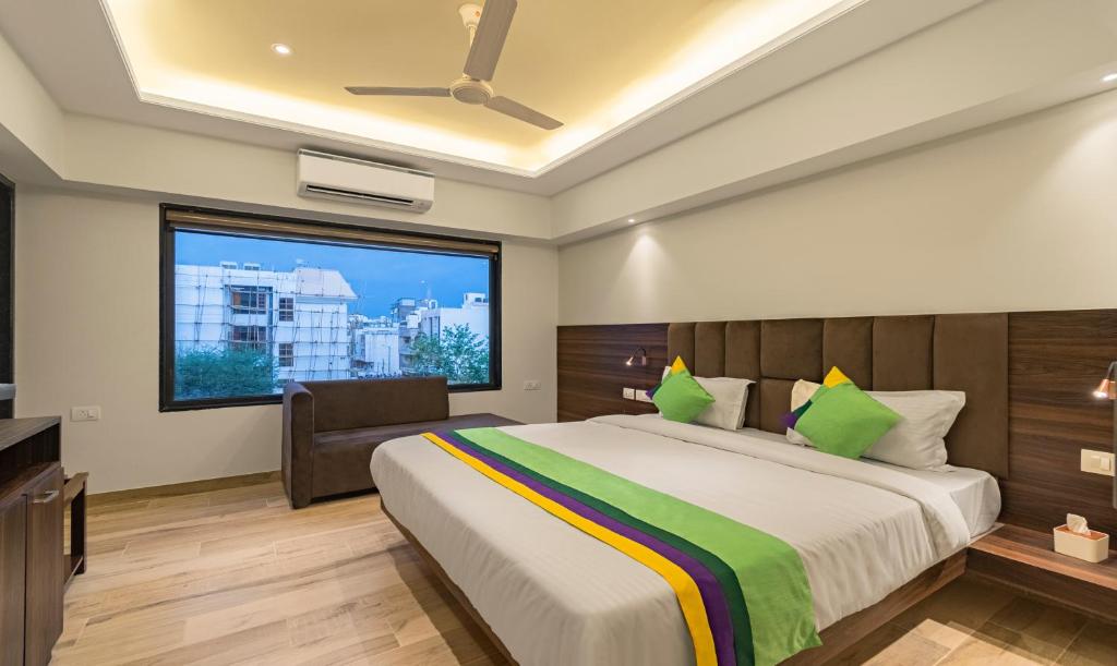 una camera con un grande letto e una finestra di Treebo Trend Pink City Grand a Jaipur
