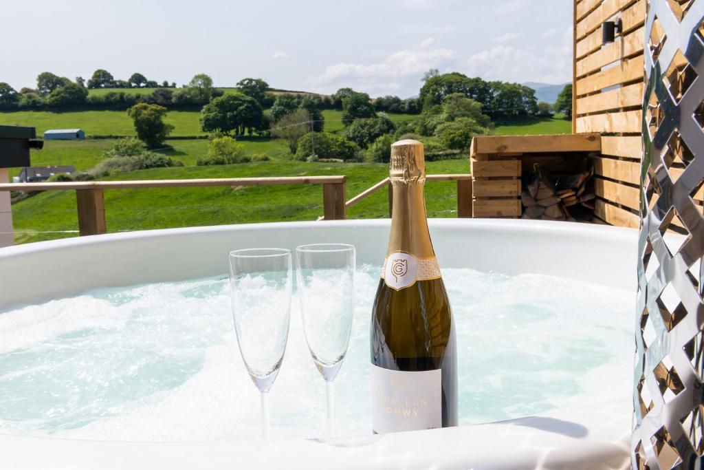 a bottle of champagne and two glasses in a hot tub at Ty Uchaf Cottage in Llansantffraid Glan Conwy