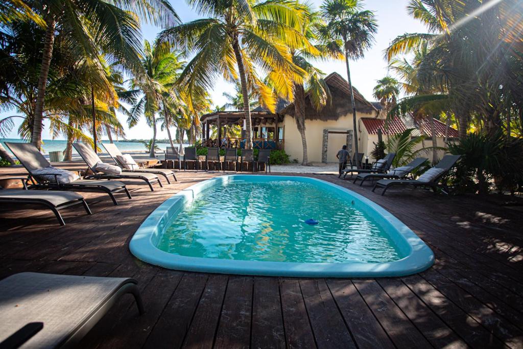 a swimming pool on a deck with chairs and palm trees at Grand Slam Fishing Lodge Tulum in Punta Allen