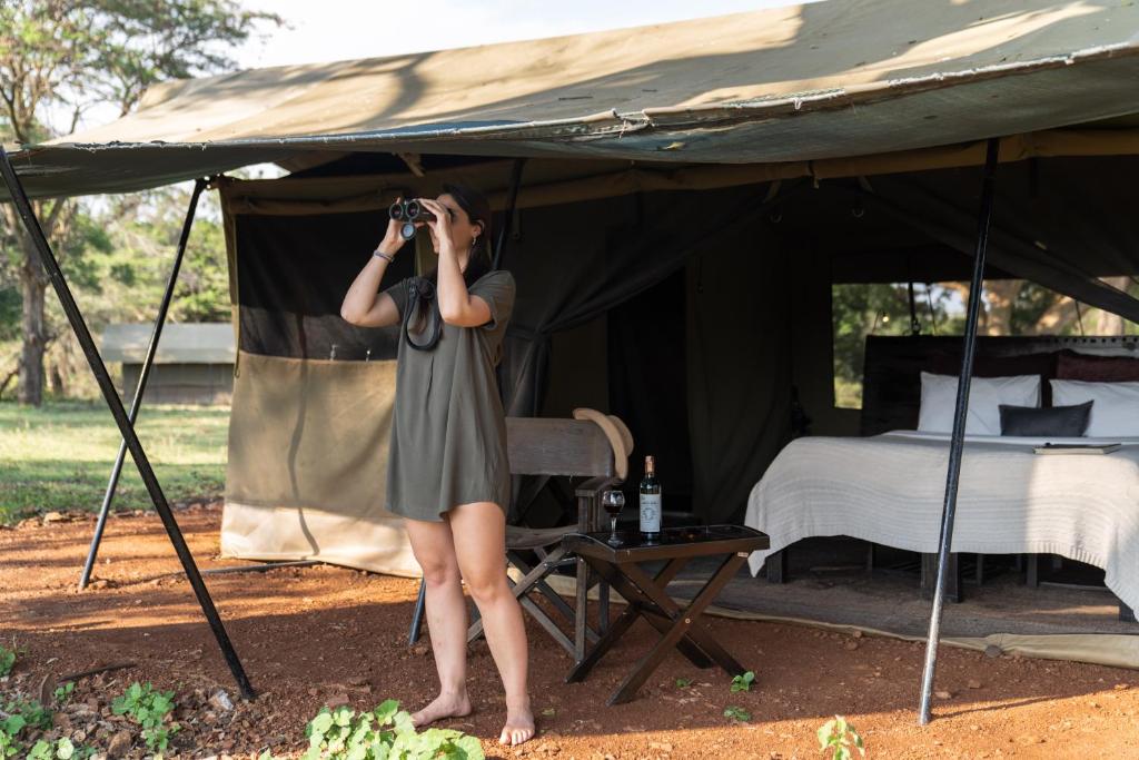 a woman taking a picture of a tent at Basecamp Adventure in Masai Mara