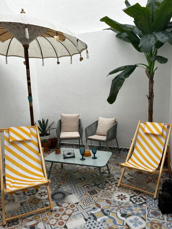 un patio con 2 sillas, una mesa y una sombrilla en Doña Josefina y Don Simón, en Almería