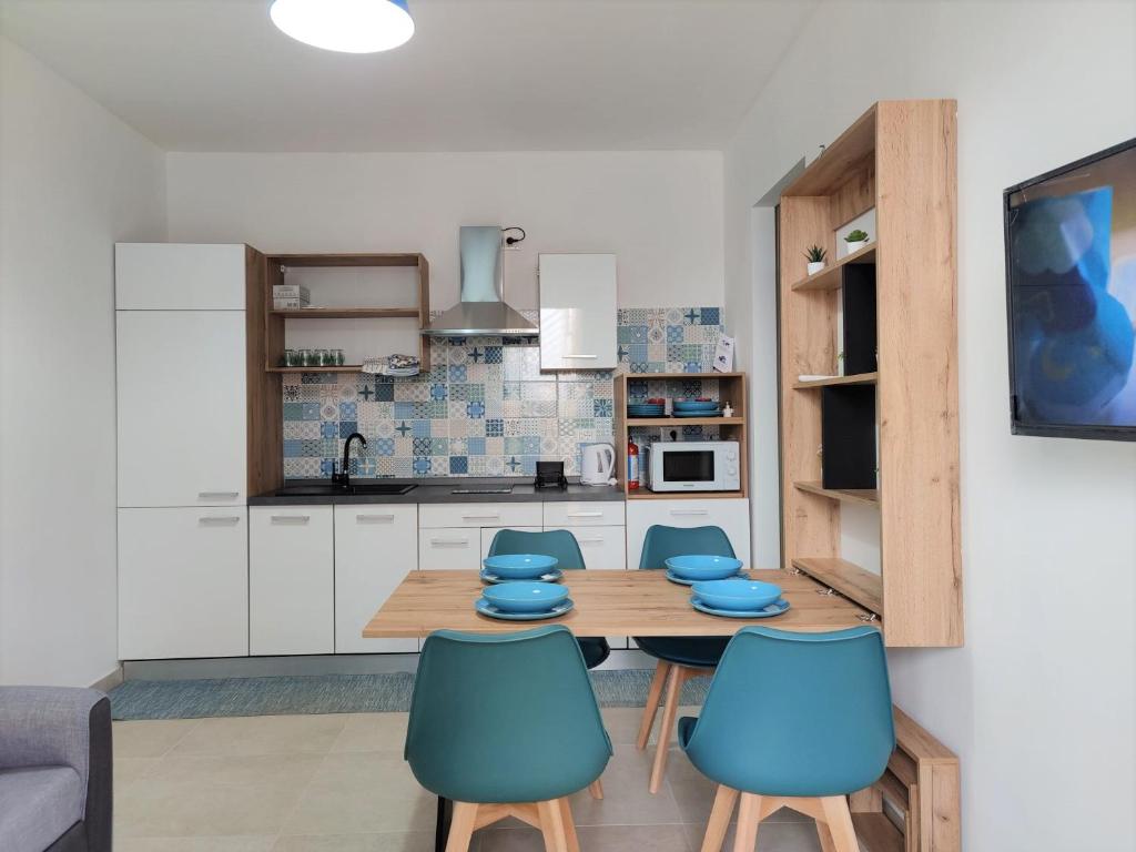 cocina con mesa de madera y sillas azules en Appartamento Girasole by Holiday World, en Pachino