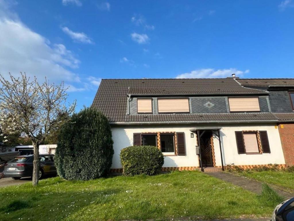 a white house with a black roof at Cozy villa with garden, balcony and parking area in Düsseldorf in Düsseldorf