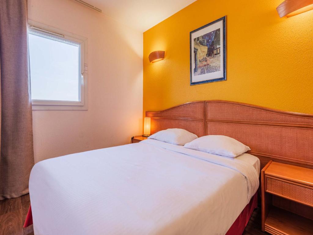 a bedroom with a white bed and a yellow wall at B&B HOTEL Strasbourg Aéroport in Holtzheim