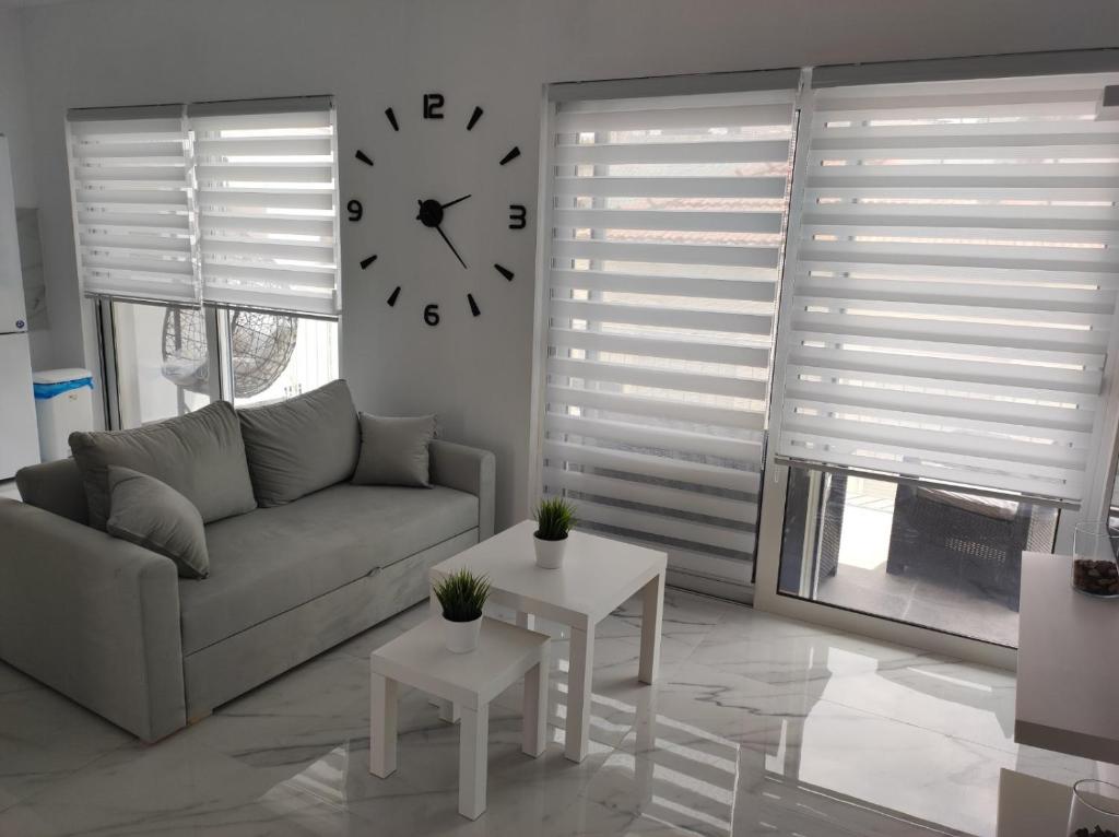 a living room with a couch and a clock on the wall at Alex Apartments Skiathos in Skiathos