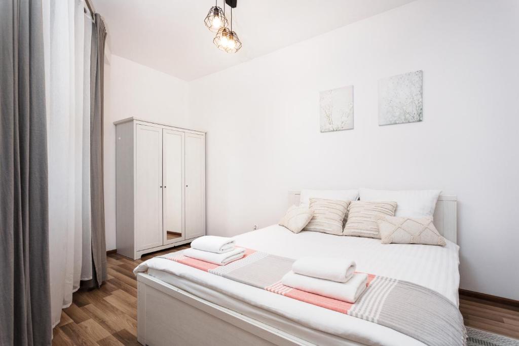 a white bedroom with a large bed with towels on it at City of the Kings-Camomile Apartment in Krakow