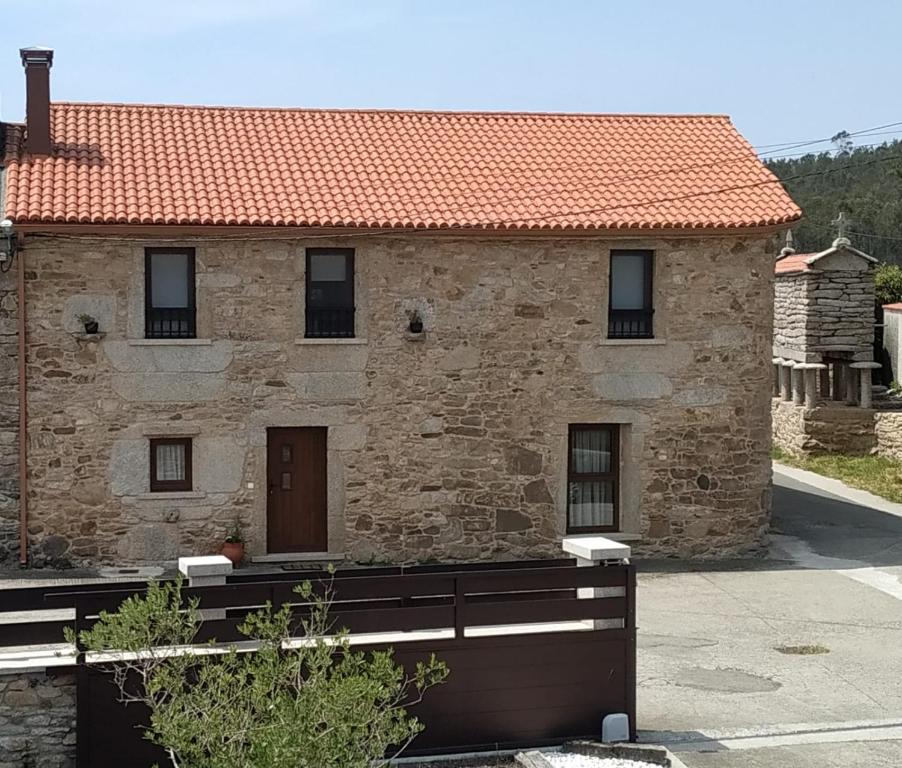 uma casa de pedra com um telhado vermelho em Casa Rural Curracho em Vimianzo