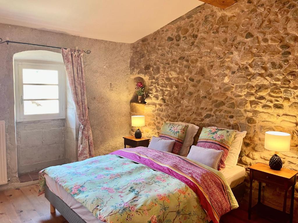 1 dormitorio con cama y pared de piedra en LE CLOS D'ALET, en Alet-les-Bains