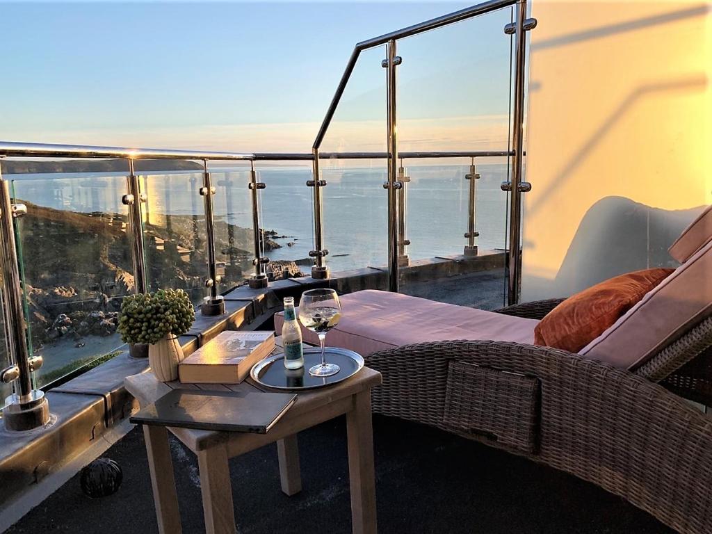 a balcony with a couch and a table with a wine glass at Watersmeet Hotel in Woolacombe