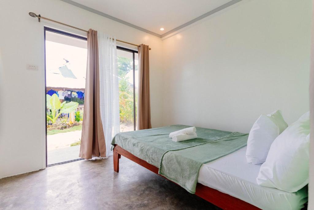 a bedroom with a bed and a large window at Kawayan Hostel in General Luna