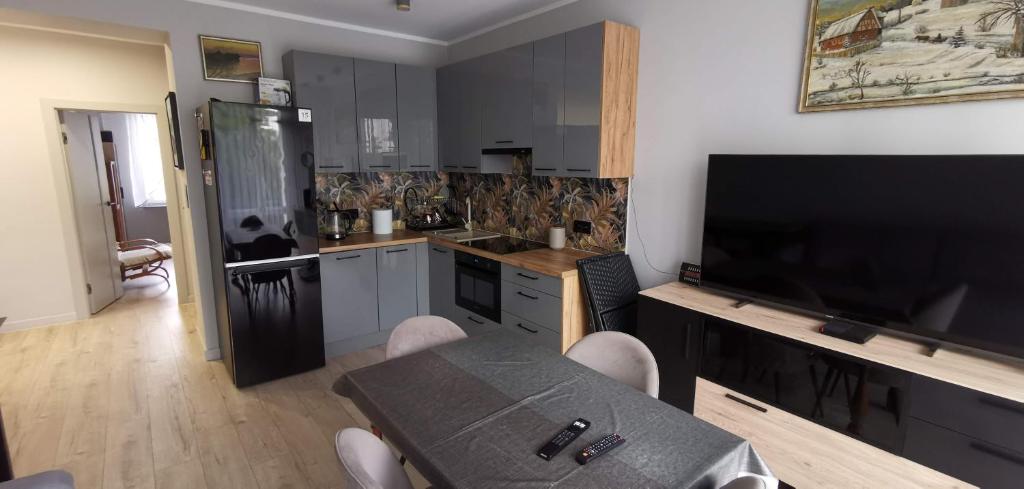 a kitchen with a table and a flat screen tv at Apartament Iława Centrum in Iława