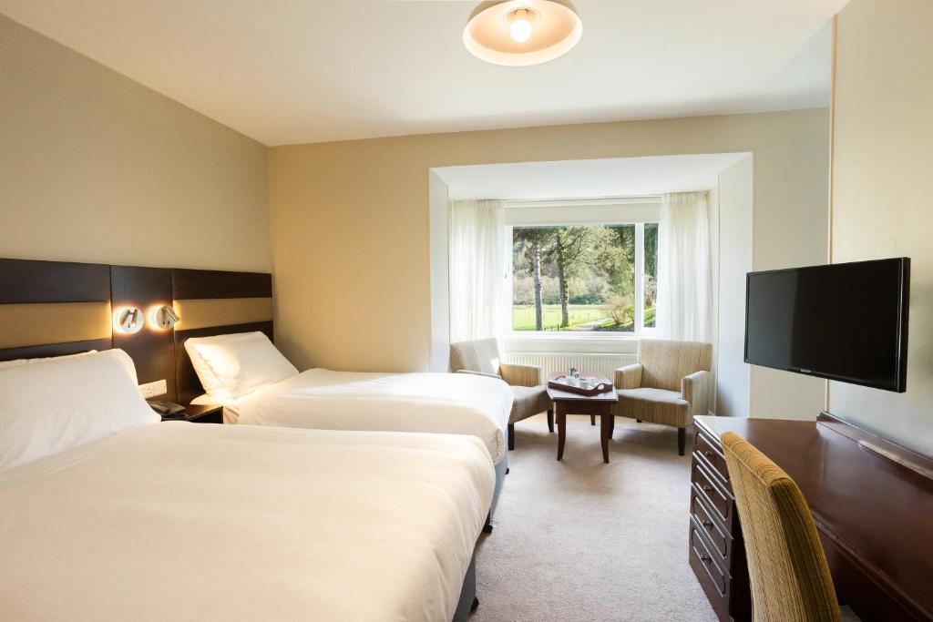 um quarto de hotel com duas camas e uma televisão de ecrã plano em The Glendalough Hotel em Laragh